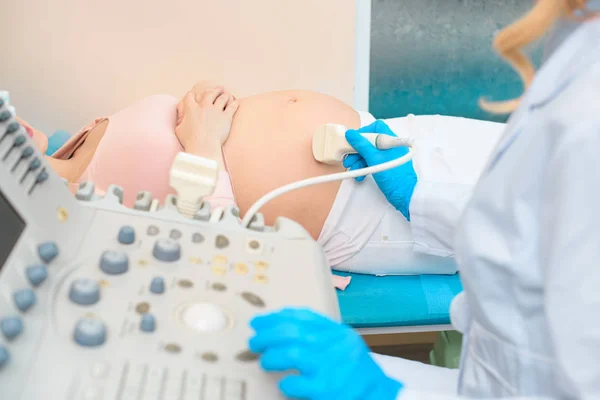 Cropped shot of obstetrician gynecologist making ultrasound scanning for pregnant woman — Stock Photo