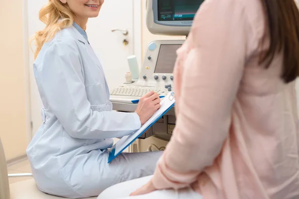 Inyección recortada de ginecólogo obstetra consulta mujer embarazada en la oficina de ecografía - foto de stock