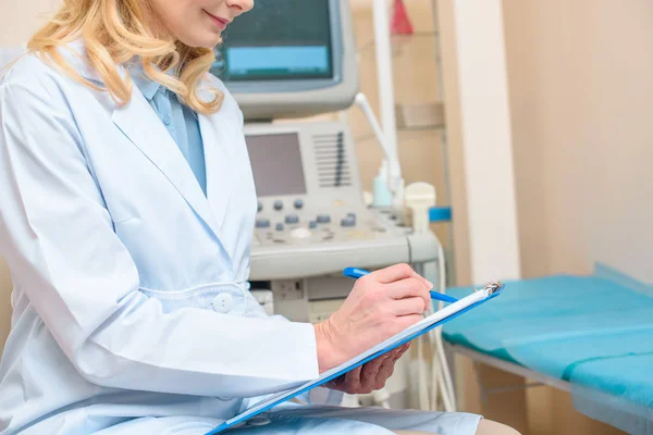 Cropped shot of obstetrician gynecologist writing in clipboard at ultrasonic office — Stock Photo