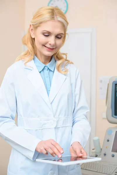 Adult obstetrician gynecologist using tablet with ultrasonic scanner on background — Stock Photo