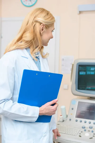 Ginecologo ostetrico con clipboard guardando scanner ad ultrasuoni — Foto stock