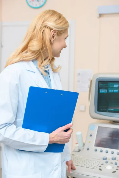 Obstetrician gynecologist with clipboard looking at ultrasonic scanner — Stock Photo