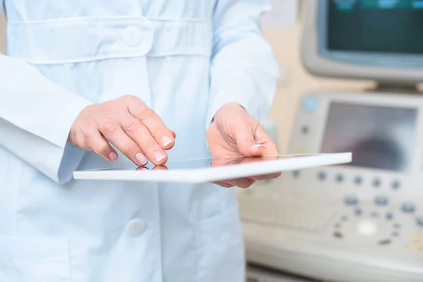 Inyección recortada de ginecólogo obstetra utilizando tableta con escáner ultrasónico en el fondo - foto de stock