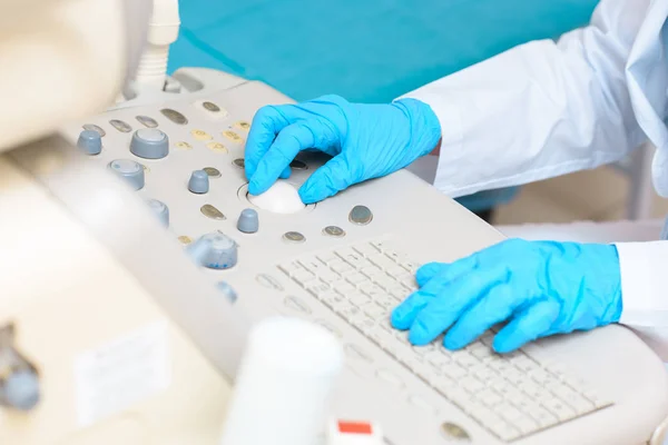 Обрезанный снимок акушера-гинеколога в синих перчатках, работающего с ультразвуковым сканером — стоковое фото