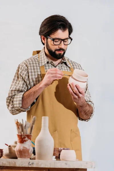 Bearded potter painting ceramic dishware in workshop — Stock Photo