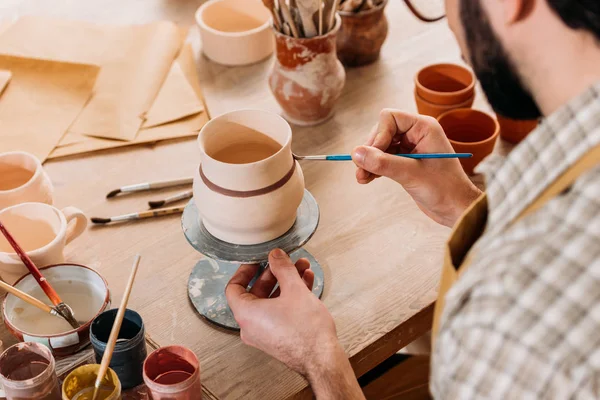 Cropped view of potter painting ceramic jug in workshop — Stock Photo