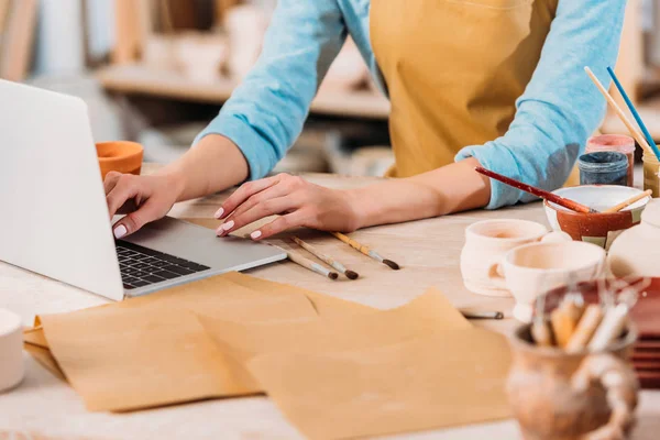 Vue recadrée de la femme travaillant avec un ordinateur portable dans un atelier de poterie — Photo de stock