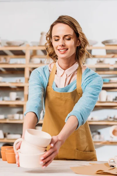 Beautiful potter with ceramic dishware in workshop — Stock Photo