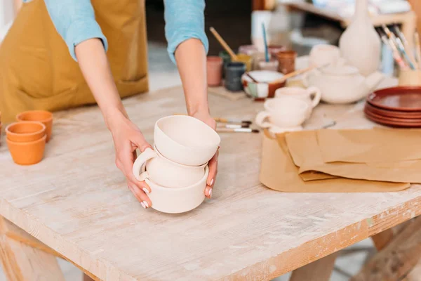 Cropped view of female potter with ceramic dishware — Stock Photo