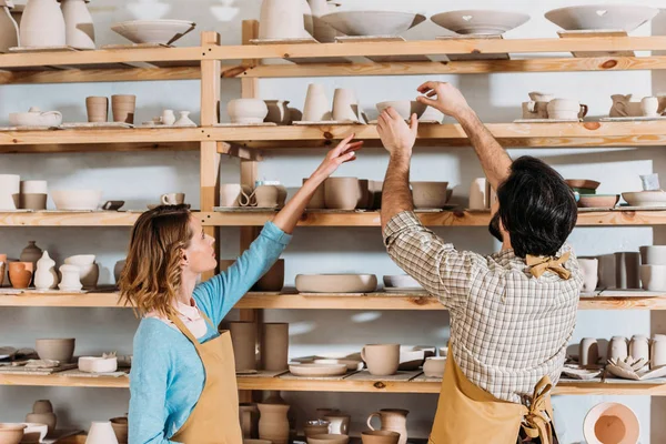 Two potters with ceramic dishware in workshop — Stock Photo