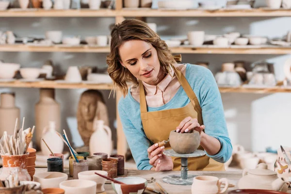 Beau potier féminin décorant bol en céramique dans l'atelier — Photo de stock