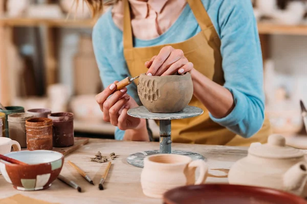 Vista ritagliato di vasaio in grembiule decorazione ciotola in ceramica in officina — Foto stock