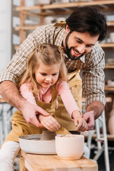 Adorable kid and teacher using pottery wheel together in workshop — Stock Photo