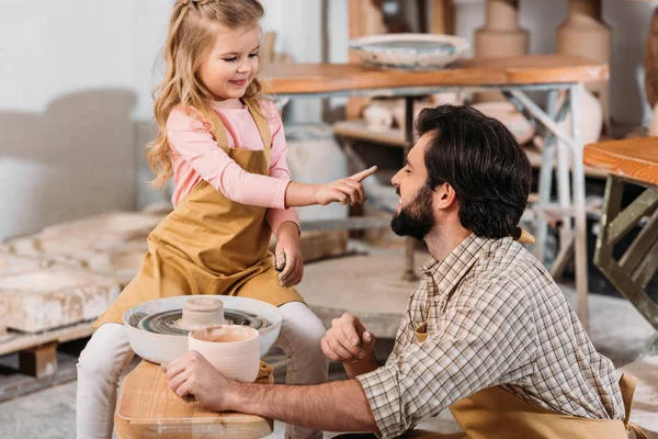 Adorable hija tocando nariz de padre en taller de cerámica - foto de stock