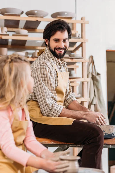 Feliz padre e hija haciendo olla de cerámica en taller de cerámica - foto de stock
