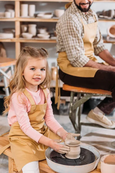 Kind bastelt Keramiktopf auf Töpferscheibe mit Lehrer in Werkstatt — Stockfoto