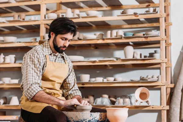 Hombre barbudo haciendo olla de cerámica en la rueda de cerámica en taller de cerámica - foto de stock