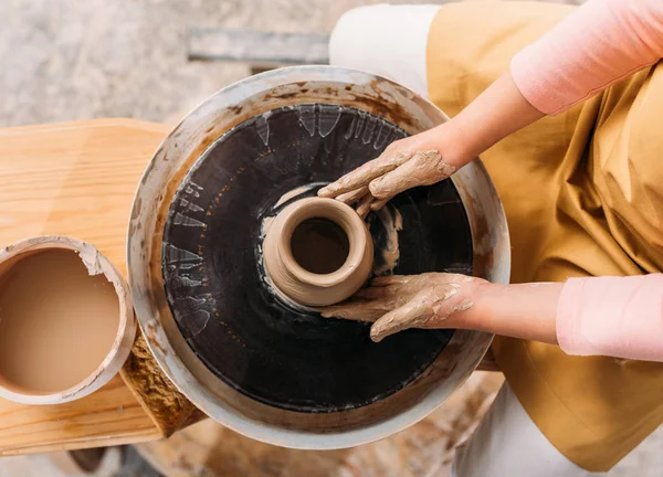 Обрезанный вид ребенка, делающего керамический горшок с глиной на гончарном круге — стоковое фото