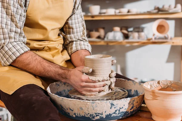 Teilansicht männlicher Hände mit Keramiktopf auf Töpferscheibe — Stockfoto