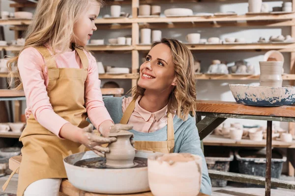 Insegnante femminile e bambino che fanno pentola in ceramica sulla ruota in ceramica in officina — Foto stock