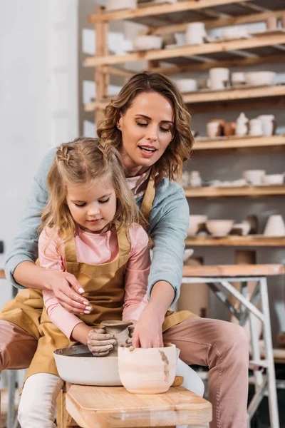 Mère et fille faisant pot en céramique sur roue de poterie ensemble — Photo de stock