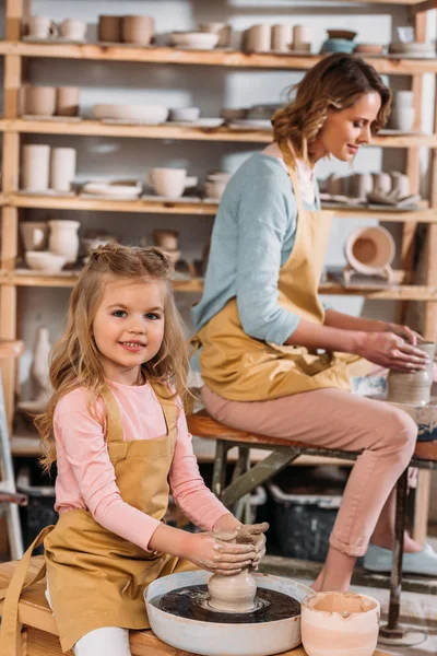 Teacher and kid making ceramic pots on pottery wheels in workshop — Stock Photo