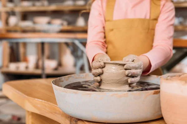 Partial view of child making ceramic pot on pottery wheel in workshop — Stock Photo