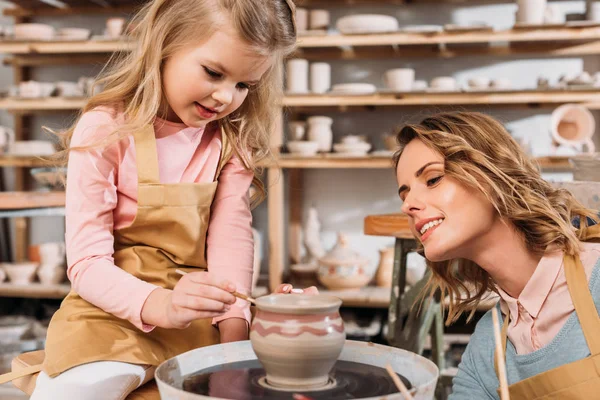 Mother and daughter painting ceramic pot in pottery workshop — Stock Photo