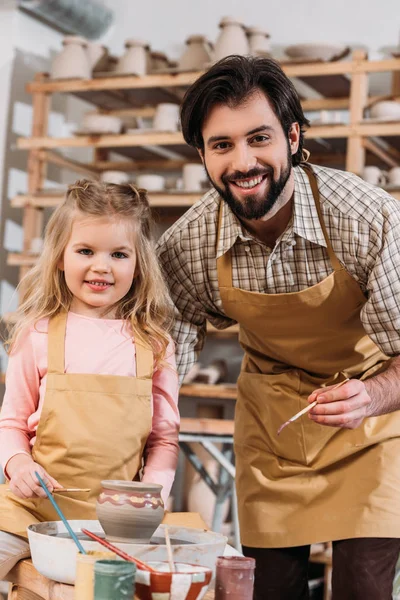 Lächelnder Lehrer und glückliches Kind bemalt Töpferkurs-Lehrerin mit Keramiktopf — Stockfoto