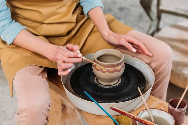 Vista cortada da mulher pintando pote de cerâmica tradicional na oficina de cerâmica — Fotografia de Stock