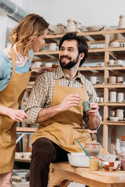 Oleiro feminino ensinando o homem como pintar cerâmica na oficina — Fotografia de Stock