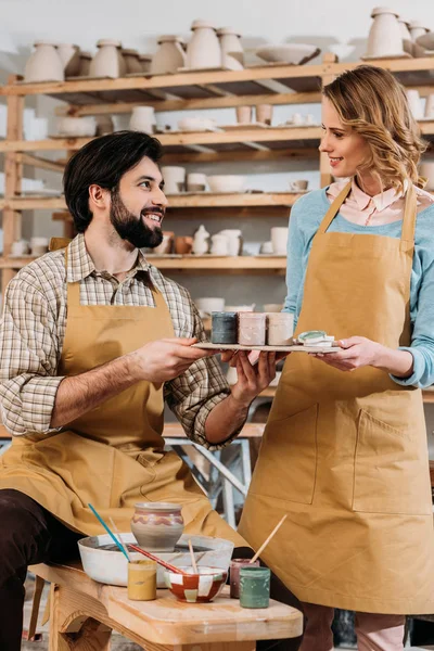Couple in aprons with paints in pottery workshop — Stock Photo