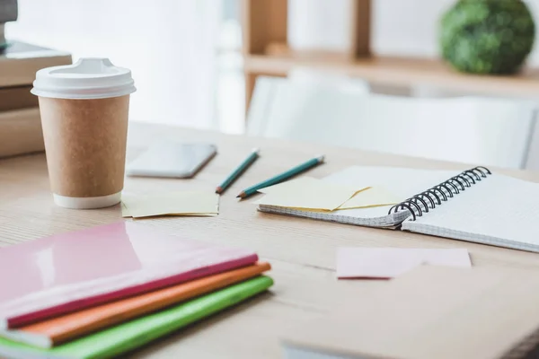 Close up of educational copybooks and disposable cup of coffee on table — Stock Photo