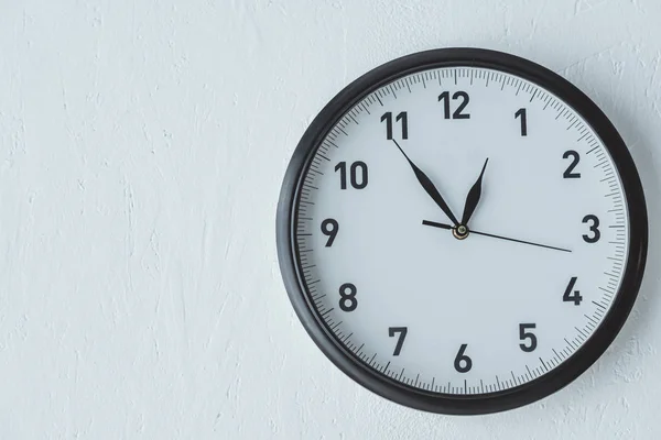 Black clock on white wall with copy space — Stock Photo