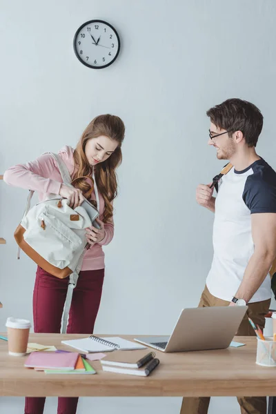 Étudiants debout à table avec des livres et un ordinateur portable — Photo de stock