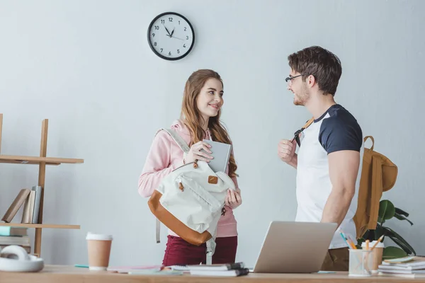 Students with backpacks standing at table with books and laptop — Stock Photo