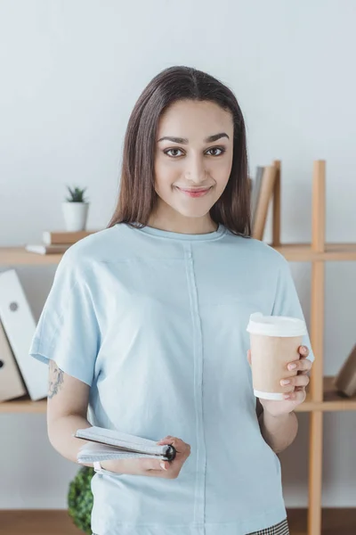 Beautiful smiling girl holding copybook and cup of coffee — Stock Photo