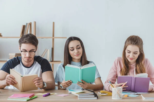 Jovens estudantes multiétnicos lendo livros — Fotografia de Stock