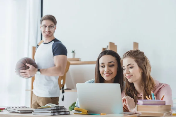 Young girls using laptop while man standing with basketball behind — Stock Photo