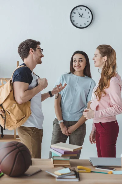 Junge glückliche Studenten stehen und reden miteinander — Stockfoto