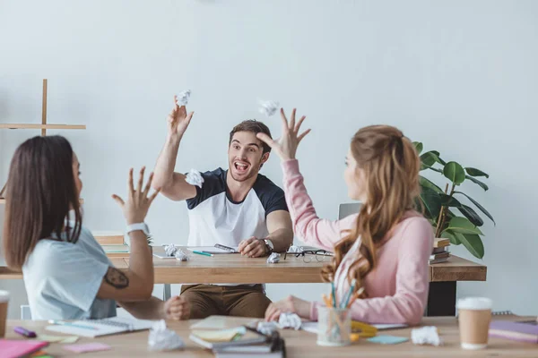 Junge Studenten amüsieren sich beim gemeinsamen Lernen mit zerknüllten Papieren — Stockfoto