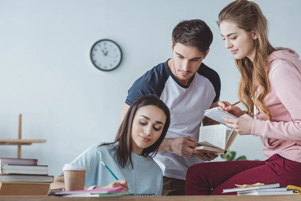 Junge Studenten sitzen am Tisch und lernen zusammen — Stockfoto