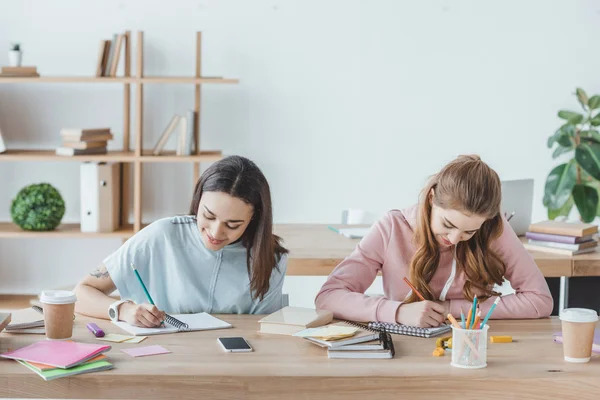 Estudiantes multiétnicos femeninos que escriben examen juntos - foto de stock