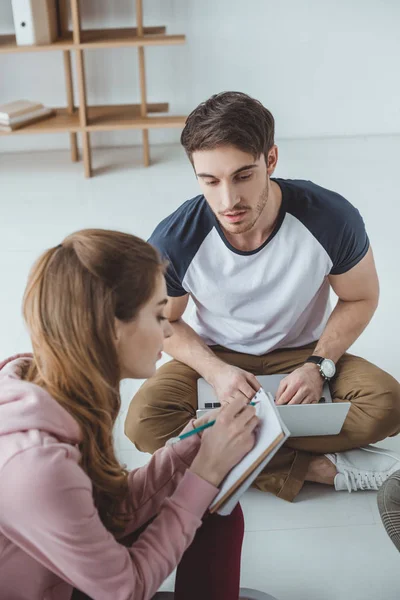 Studenten nutzen Laptop und schreiben im Copybook während des gemeinsamen Lernens — Stockfoto