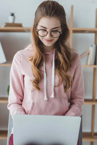 Blonde étudiante assise et utilisant un ordinateur portable — Photo de stock
