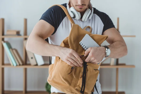 Обрізаний вид студента з навушниками, рюкзаком і блокнотом — стокове фото
