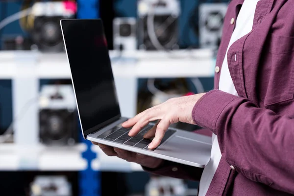 Cropped shot of computer engineer working with laptop at cryptocurrency mining farm — Stock Photo