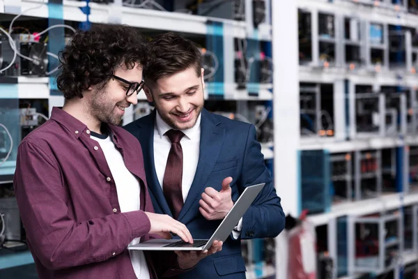 Happy young businessman and computer engineer working together at ethereum mining farm — Stock Photo