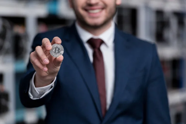 Cropped shot of smiling businessman holding bitcoin at cryptocurrency mining farm — Stock Photo