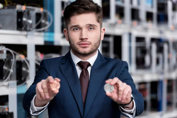 Handsome young businessman holding bitcoins at cryptocurrency mining farm — Stock Photo